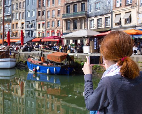girl sitting on a pier and taking a shot of honfle 2025 10 15 15 27 08 utc